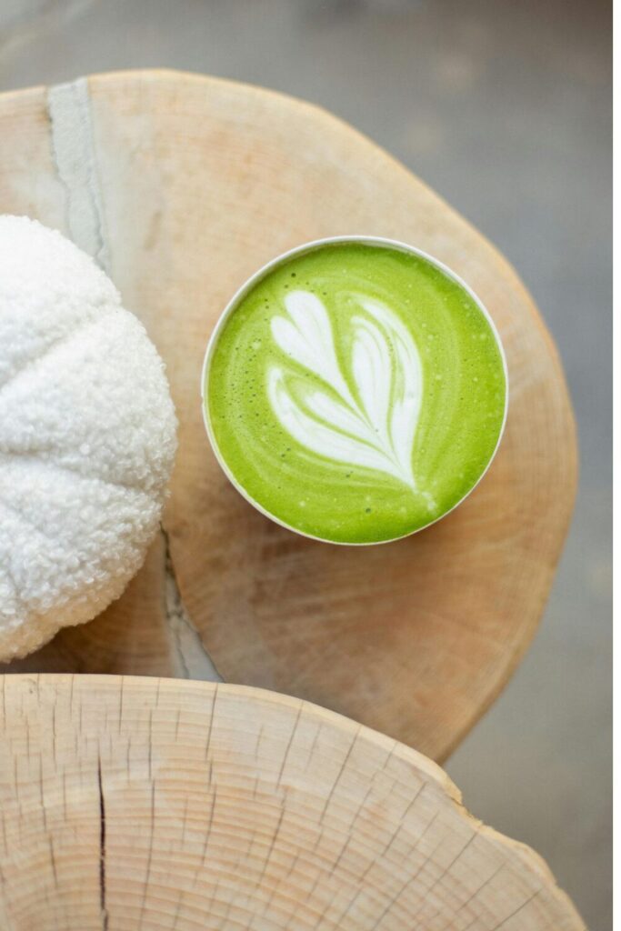 Matcha latte szív alakú tejhabbal egy fatönkön, közeli nézetből