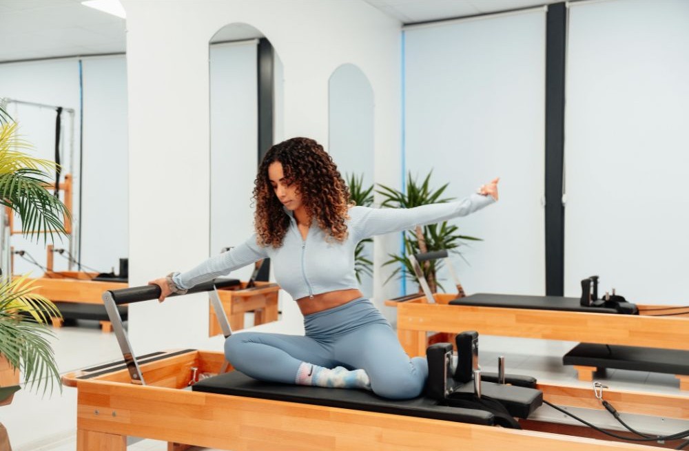 Nő pilateszik reformer gépen stúdióban – álloképesség és regeneráció támogatása sporttal