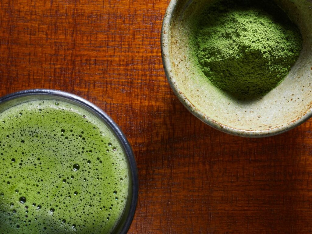 Matcha latte pohárban és matcha por tálban