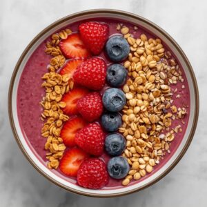 Smoothie tál felülről, granolával, szeletelt eperrel és áfonyával díszítve