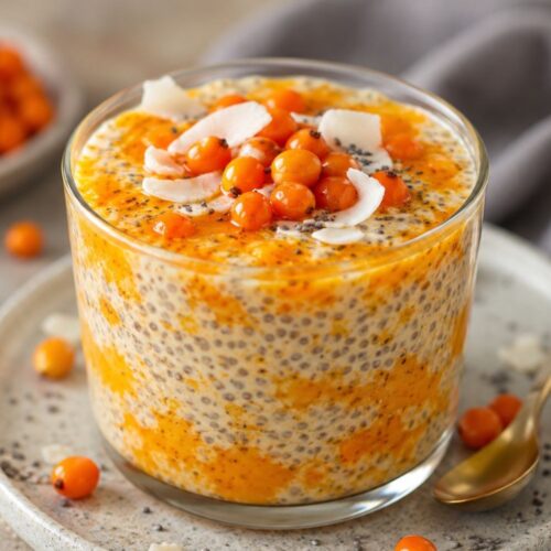 Homoktövis chia puding pohárban, kókuszreszelékkel és friss bogyókkal díszítve