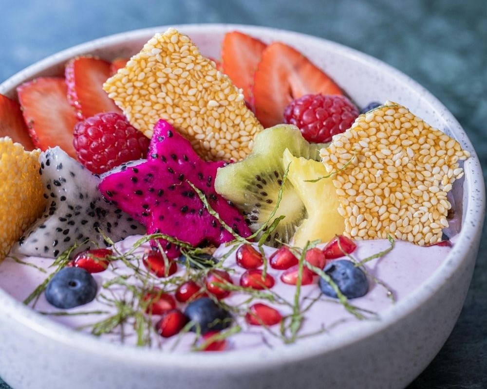 Smoothie bowl sárkánygyümölccsel, kiwivel és gránátalmával díszítve, tápláló diétás reggeliként